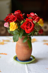 bouquet of colorful roses in the clay vintage vase at the table