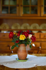 bouquet of colorful roses in the clay vintage vase at the table