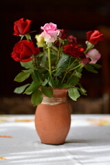 bouquet of colorful roses in the clay vintage vase at the table