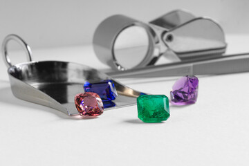 Natural coloured gem stones closeup on the white background. Emerald, Sapphire, Amethyst, Spinel, Tourmaline.