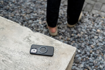 A man in a white shirt is walking past a table with a cell phone on it. The phone is an iPhone