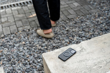 A man in a white shirt is walking past a table with a cell phone on it. The phone is an iPhone