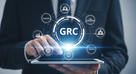 Businessman using digital tablet with a hologram of GRC acronym. A concept for governance, risk and compliance, information technology, business management and strategy.