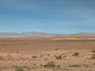 Vast desert landscape with distant mountain range under a clear blue sky in Morocco