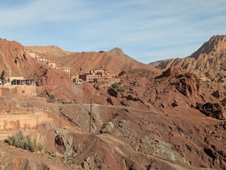 Fototapeta premium Scenic view of a Moroccan village nestled in the red rocky mountains under a blue sky