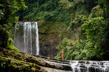 Girl standing in front of a waterfall in the jungle