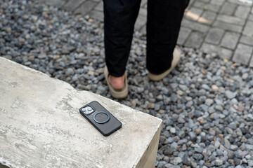 A man in a white shirt is walking past a table with a cell phone on it. The phone is an iPhone