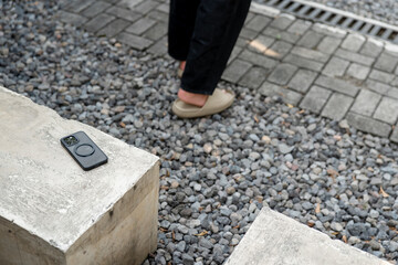 A man in a white shirt is walking past a table with a cell phone on it. The phone is an iPhone