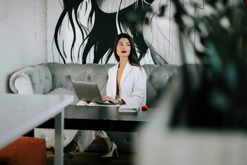 Model working on laptop in stylish indoor space with modern art and elegant decor