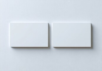 Two blank white business cards, slightly raised, on a plain white surface