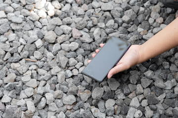 A hand holding a black object. The object is rectangular and has a black and white pattern. It is made of leather