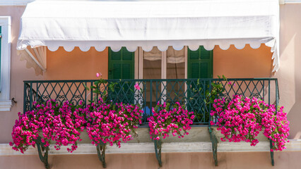 Charming balcony with bright pink flowers in Mediterranean style.