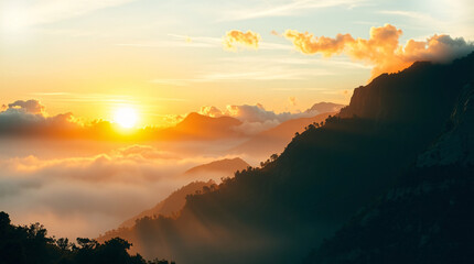 A captivating sunrise casting a warm golden light over a series of mountain ridges enveloped in a delicate layer of morning mist.