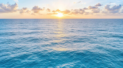 Obraz premium Serene ocean waves reflecting sunlight with soft clouds in sky at sunset