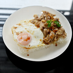 Thai basil chicken with fried egg on a white plate