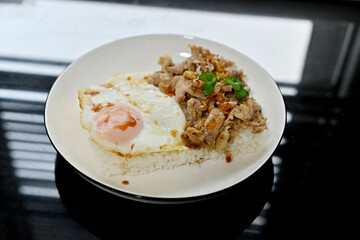 Thai basil chicken with fried egg on a white plate
