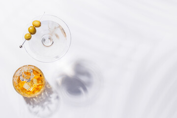 A sleek composition of a whiskey glass on the rocks paired with a martini cocktail