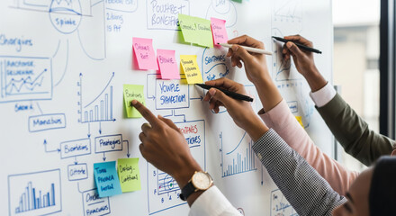 Close up of business team brainstorming on whiteboard, colleagues collaborating on project strategy using sticky notes and drawing charts in office meeting