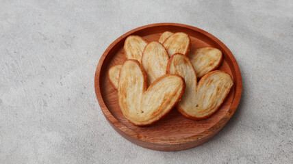 Delicious Palmier butterfly puff pastry cookie in heart shape for Valentine's day dessert concept. Sweet puff pastry, palmier cookies in close up view