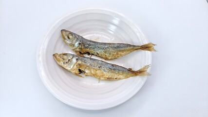 two pieces of dried or salted fish on a white plate. isolated on white background