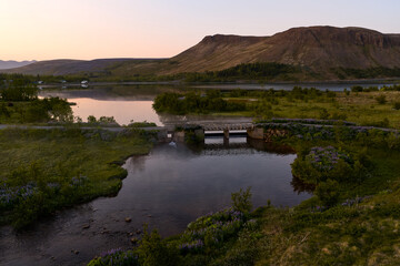 Small bridge crossing calm river at sunset in mosfellsbær, iceland