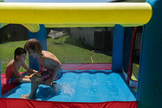 Two boys playing inside a wet inflatable bounce house