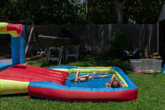 Kids relaxing in inflatable backyard pool on a sunny day