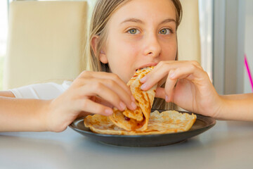 close-up stock photo of a happy 11-year-old pre teen girl enjoying pancakes and crepes at home, capturing a joyful lifestyle moment perfect for themes of childhood, breakfast, and family life
