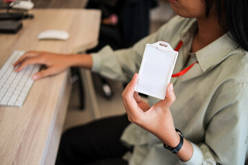 Businesswoman Sitting At Wooden Desk And Holding Blank White ID Card With Red Lanyard