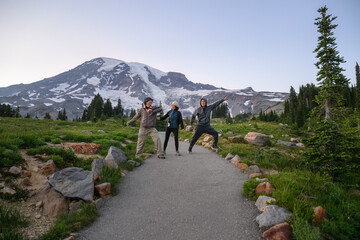 Three friends having fun at Paradise Valley. Mt Rainier in the background. Mt Rainier National Park. Washington State.