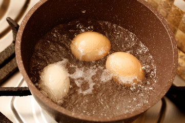 Three eggs are cooking in a pan on a stove