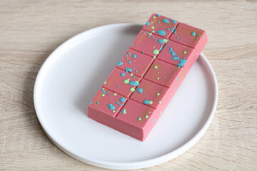 Ruby Dubai chocolate bar decorated with a colorful pattern resting on a white plate