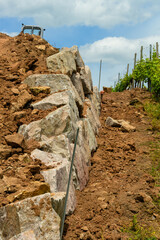 Chantier en cours : les premières pierres d'un mur de soutien dans le vignoble en terrasse sur les coteaux alsaciens