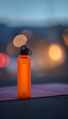 Minimalist orange hydration bottle on gym mat at dusk