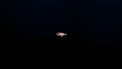 Single hand reaching out from the darkness mysterious conceptual image