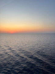 Obraz premium Breathtaking sunset over the sea photographed from the deck of a cruise ship. The golden light reflects on the calm ocean waves