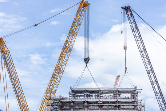 Construction site with construction crawler cranes and multi storey unfinished buildings, Many high rise cranes and industrial construction equipment, Contruction site blue sky background.