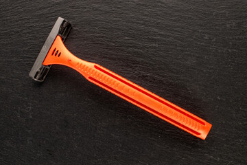 Disposable razor on slate stone, close-up. Top view.