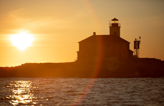 orange sunflare silhouettes island lighthouse