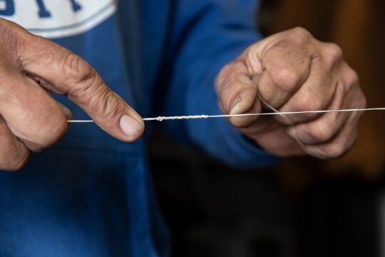 A fisherman ties knot in fishing line