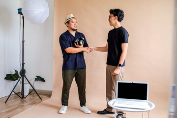 Asian Photographer Man And Model Man Shake Hands In A Studio After A Photo Session
