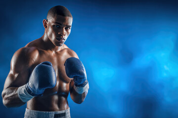 Muscular boxer fighter young man with blue boxing gloves posing in front of blue background showing strength and focus