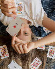 close-up stock photo of an 11-year-old pre teen girl smiling and holding a winning hand of playing cards, perfect for game night, leisure, and childhood fun concepts