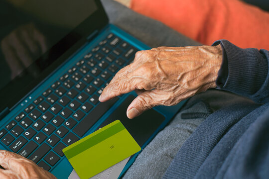 Elderly man exploring digital world in retirement,making an online purchase using a credit card and a laptop