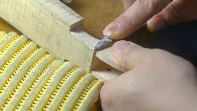 Skilled luthier carefully rasping wooden instrument part, revealing intricate handcrafting details during delicate shaping process for stringed musical creation - Powered by Adobe