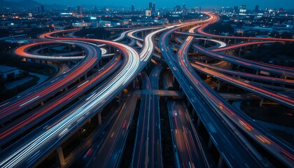 Aerial view of an intricate multilane highway interchange illuminated by night city lights with