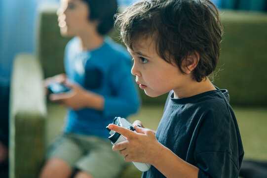 Child playing video game console at home with focus and concentration