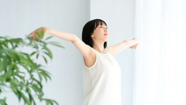 ストレッチ・深呼吸をする白い服の若い女性