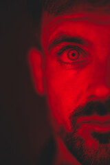 A mysterious gaze pierces through the crimson frame, revealing intensity and hidden stories