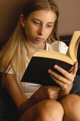 close-up stock photo of an 11-year-old pre teen girl reading a book at home, capturing a cozy lifestyle moment perfect for education, leisure, and childhood learning themes